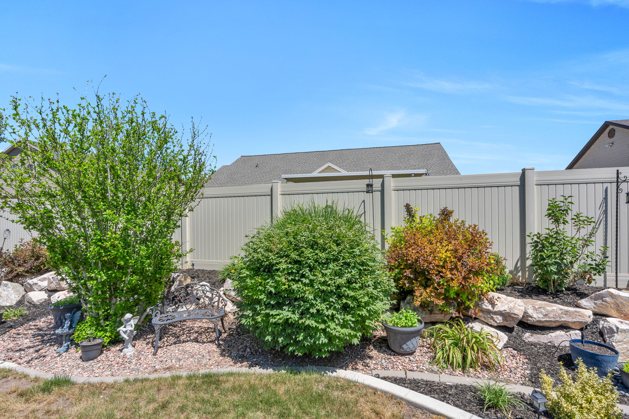 Landscaped garden bed featuring diverse shrubs, rock accents, and dark ground cover