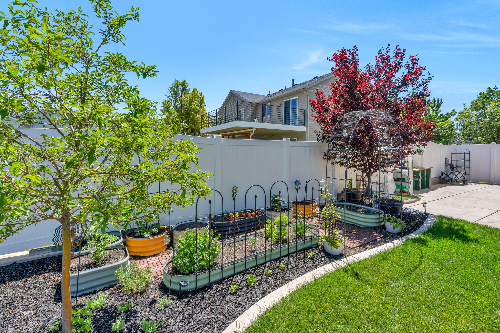 Landscaped backyard featuring a dedicated garden area with raised beds and brick paver accents