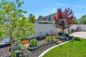 Landscaped backyard featuring a dedicated garden area with raised beds and brick paver accents