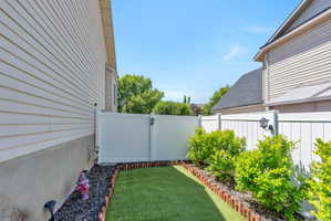 Private side yard featuring artificial turf and defined planting beds with mature shrubs