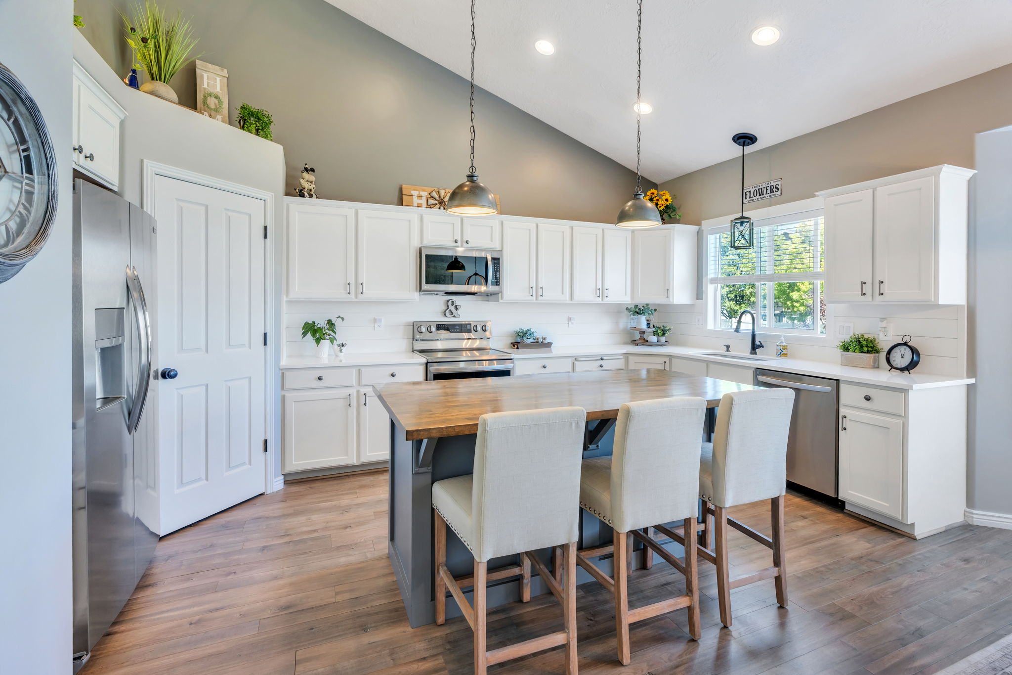 Kitchen featuring white cabinetry, wood-finish flooring, stainless steel appliances, a center island with a wood countertop, and vaulted ceilings