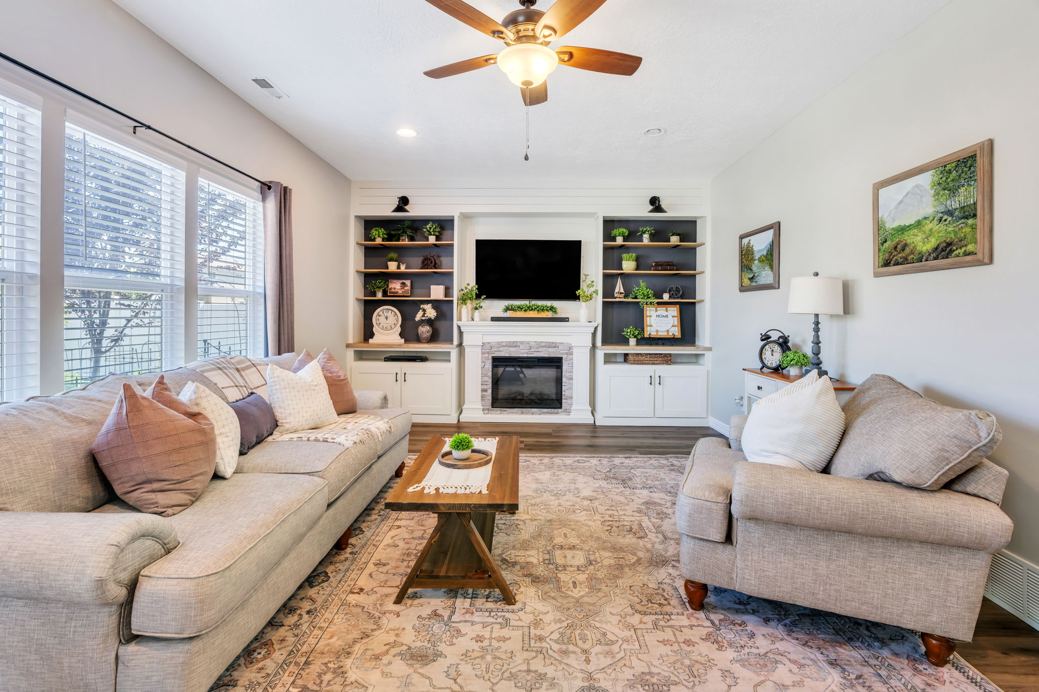 Living area featuring a ceiling fan, wood-finish flooring, and built-in shelving with integrated cabinetry