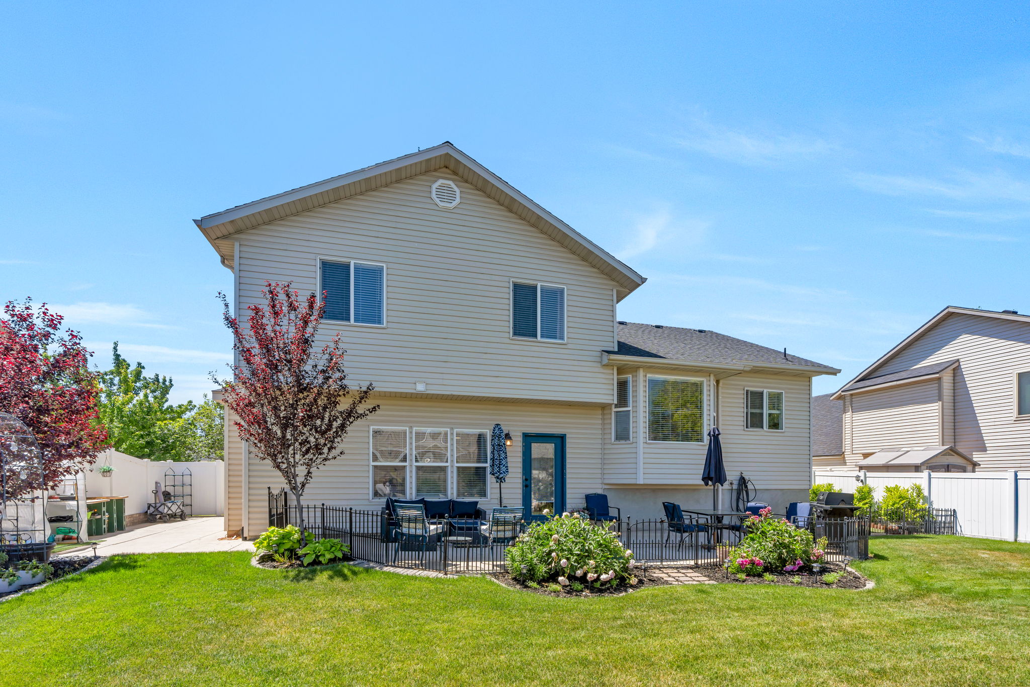Expansive backyard featuring a manicured lawn, a paved patio area, and mature landscaping