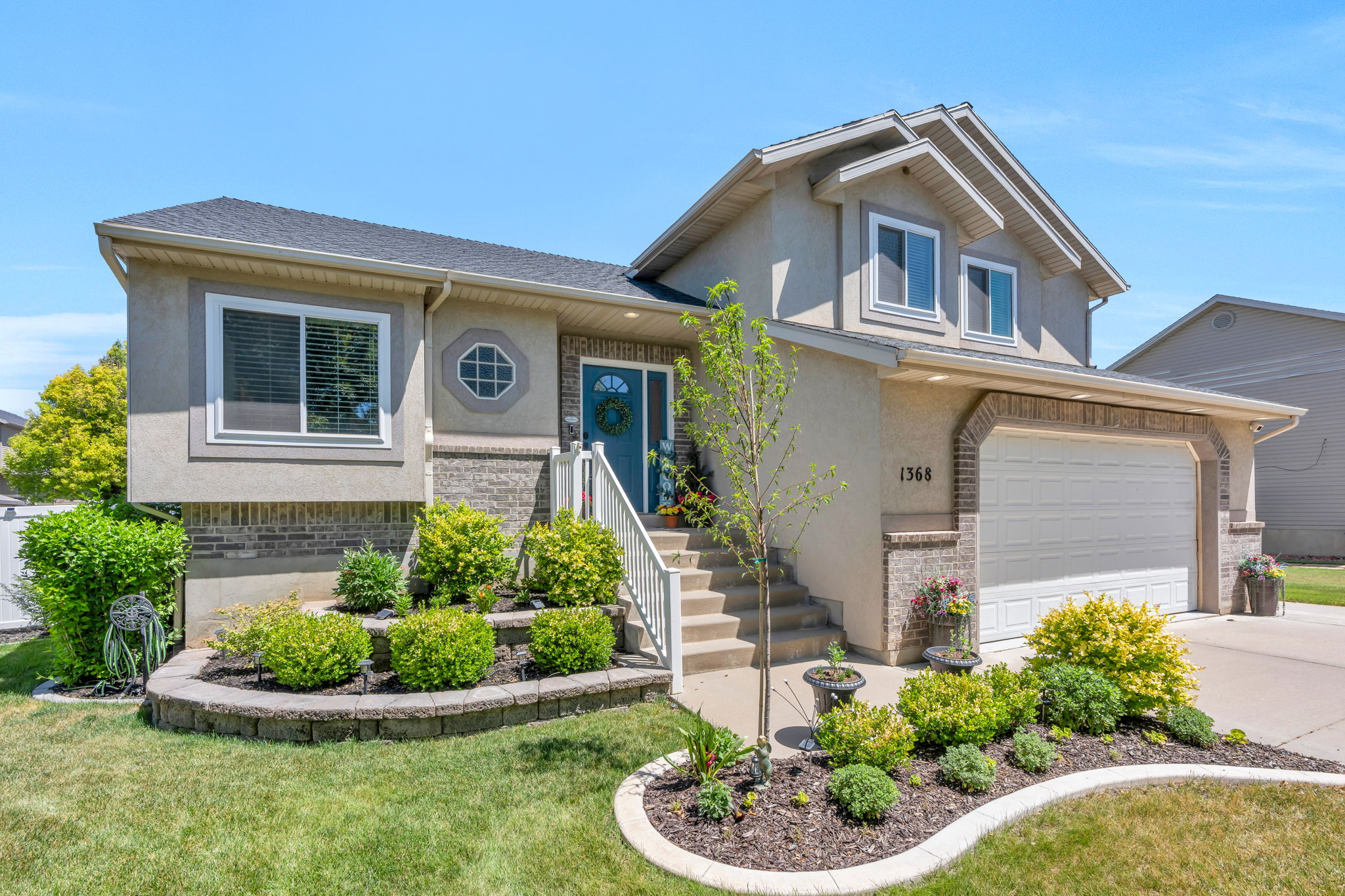 Stucco exterior with brick accenting, a two-car garage, and a front entry with a blue door