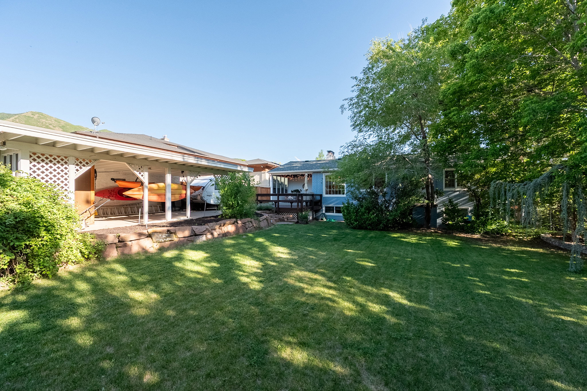 Spacious backyard featuring a manicured lawn and mature trees, backs onto unused area of Bonneville Golf Course.