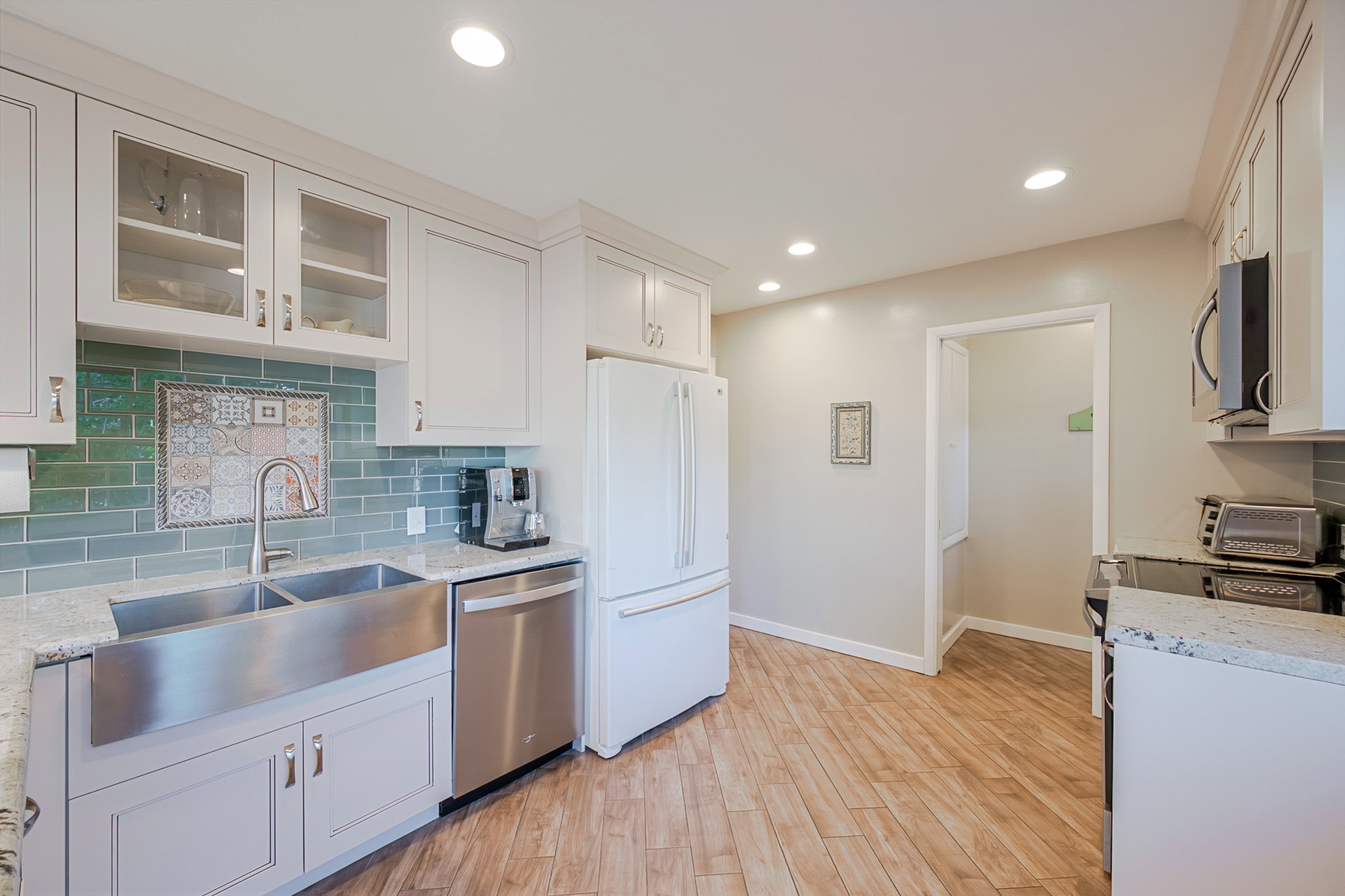 Newer open floor plan Kitchen featuring light cabinetry, hardwood floors, recessed lighting, and a stainless steel farmhouse sink