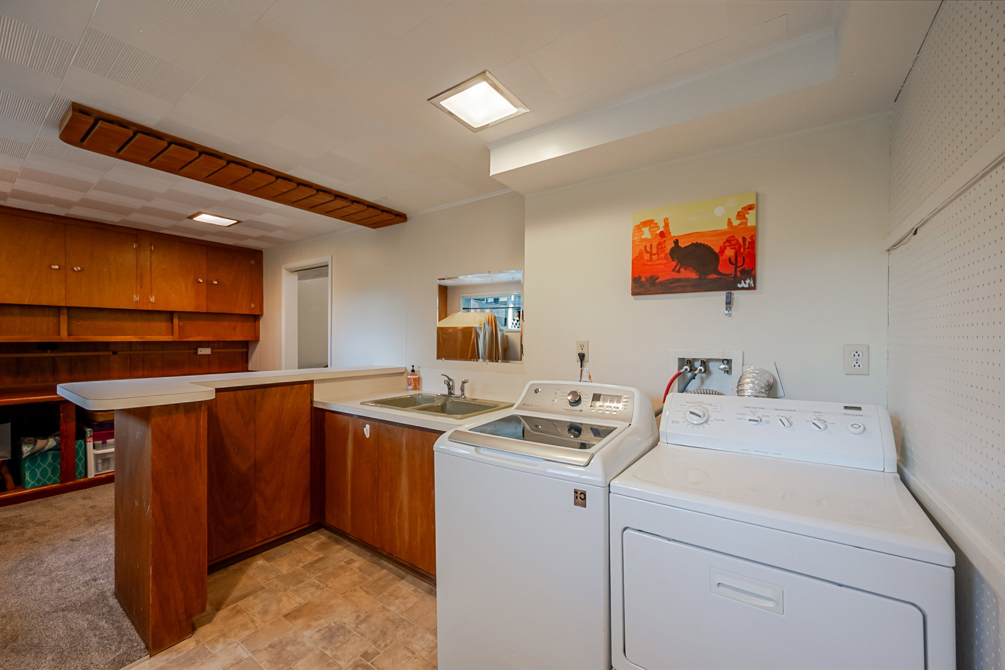 Utility room featuring wood-finish cabinetry, a double basin sink, and a built-in counter space, could easily serve as second kitchen for an ADU.