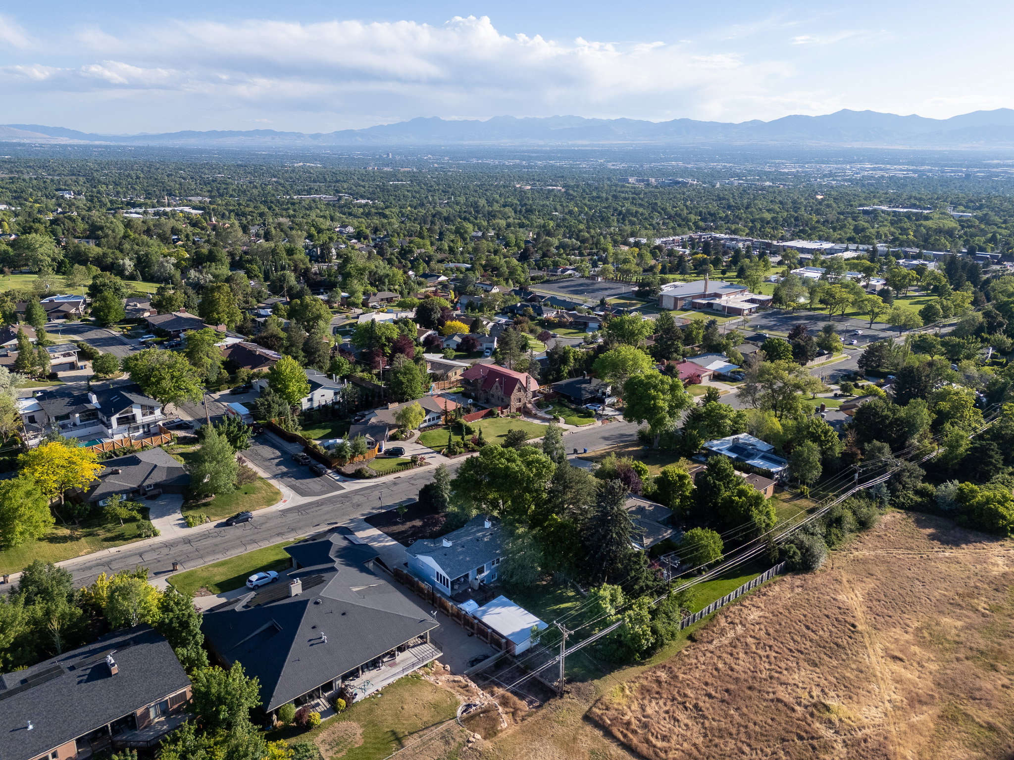 Expansive aerial perspective showcasing a residential neighborhood with a backdrop of distant mountains