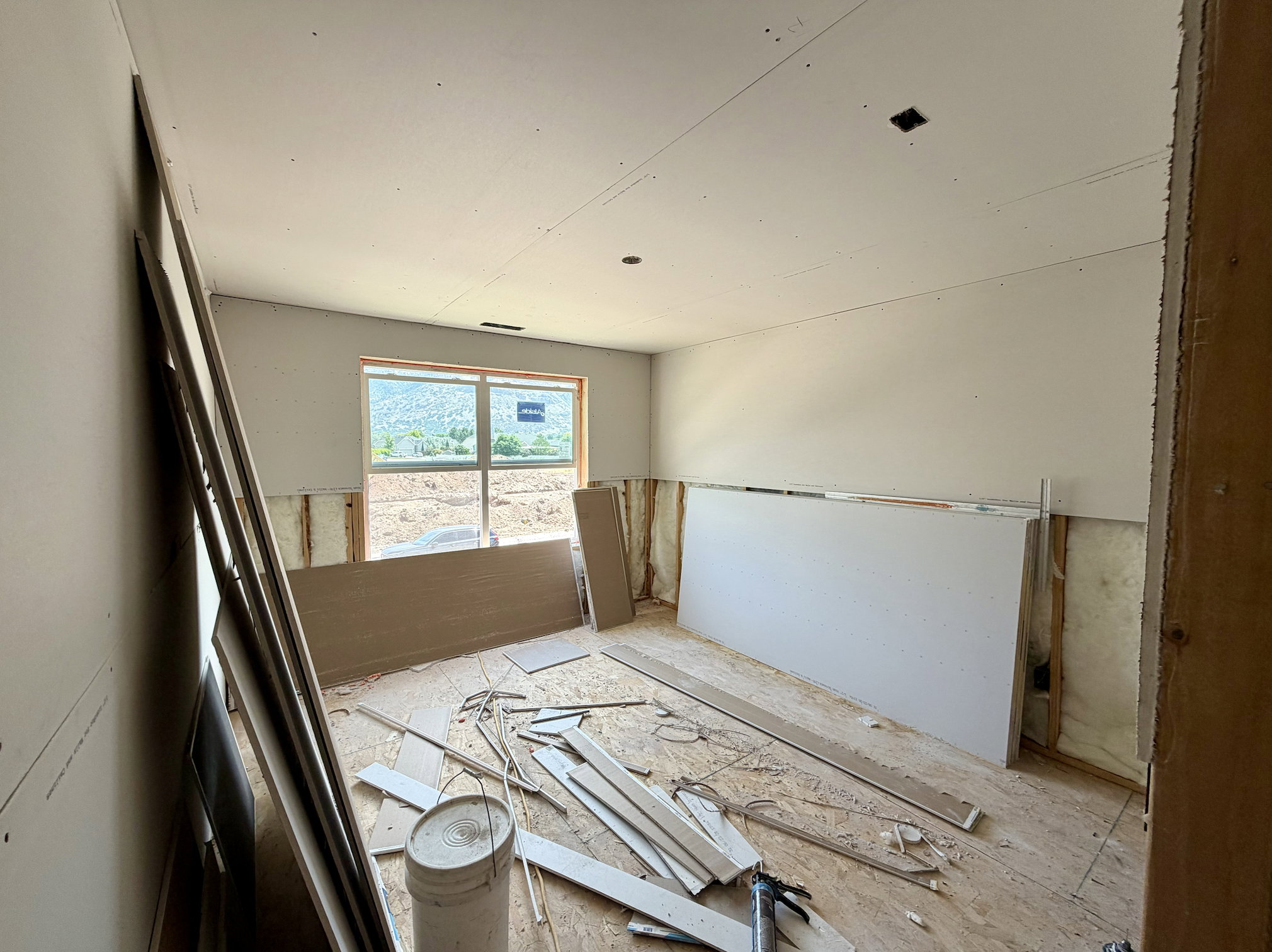 Unfinished interior room featuring a large window, recessed ceiling light fixtures, and wall studs