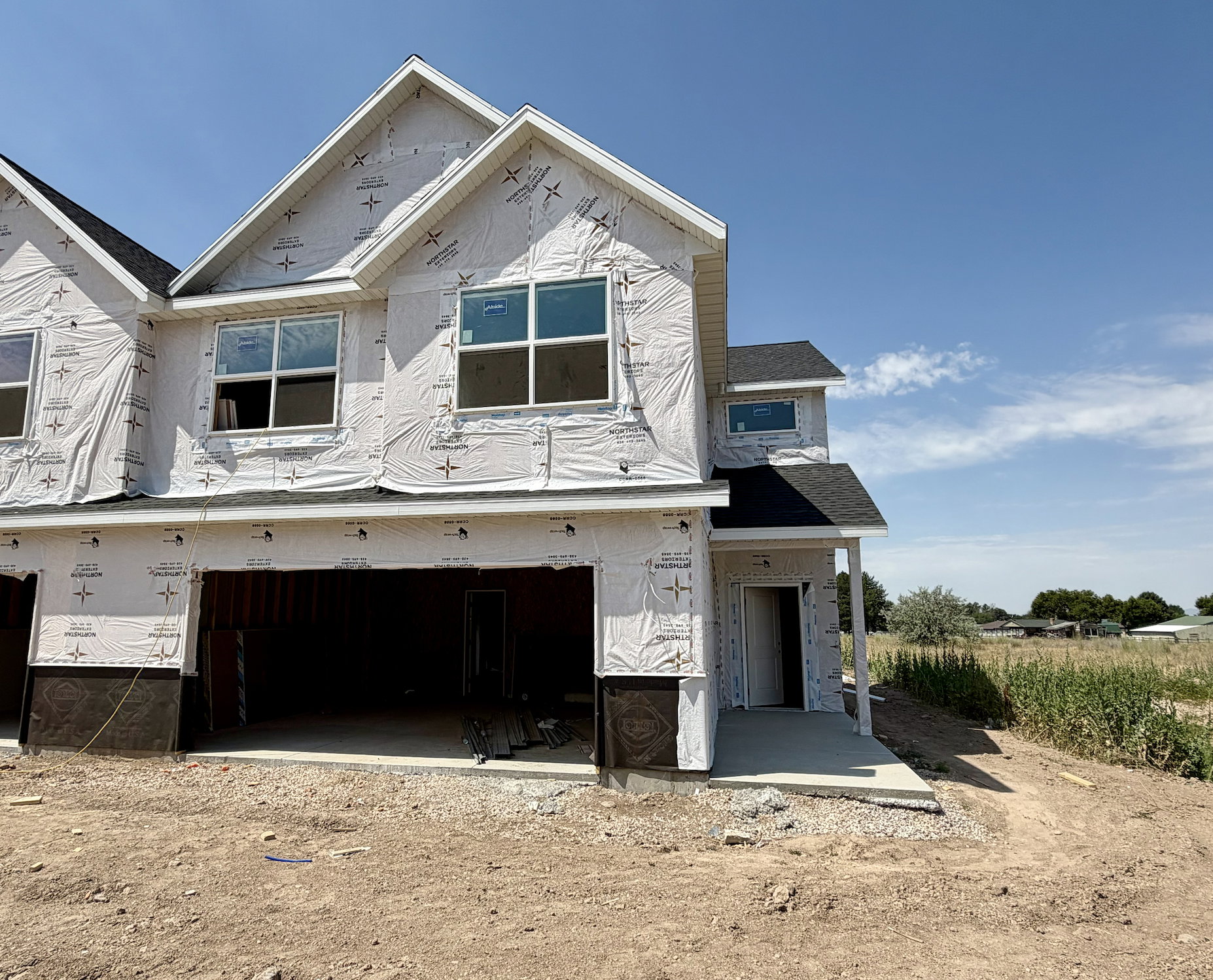 New construction exterior featuring multiple windows and a dual-bay garage opening