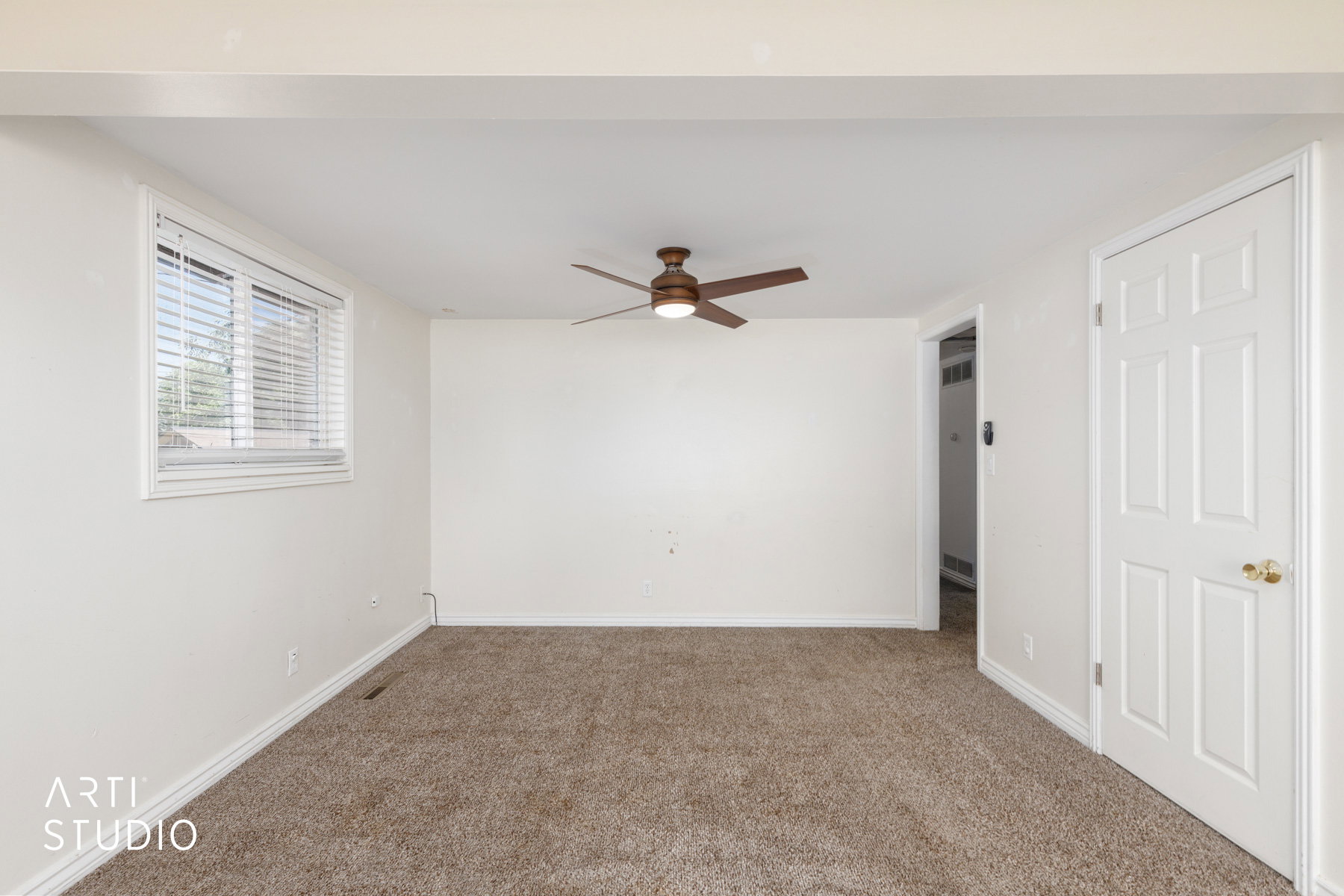 Carpeted room featuring a ceiling fan, white paneled door, and a window with blinds