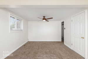 Carpeted room featuring a ceiling fan, white paneled door, and a window with blinds