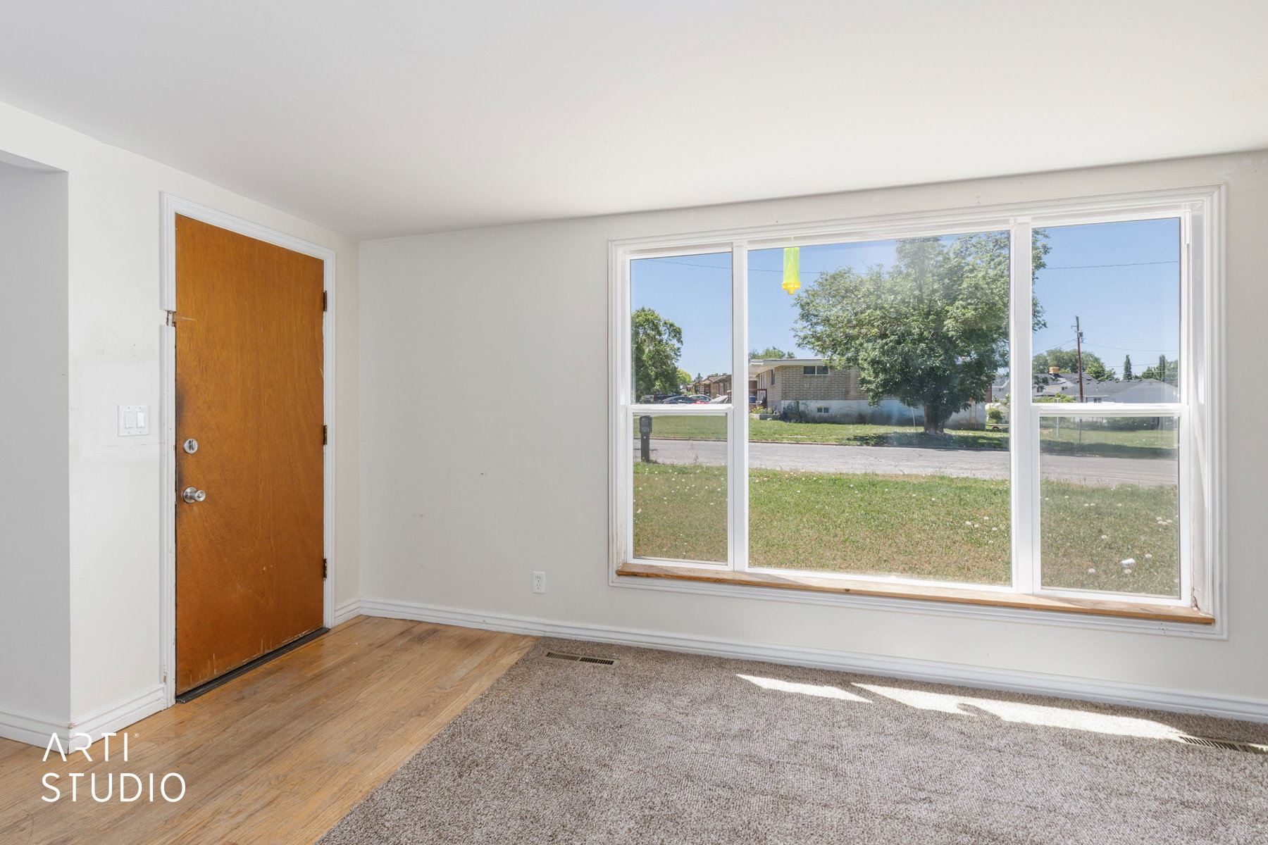 Front entry area featuring wood-finish flooring, a solid wood door, and a large picture window with white trim
