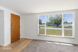 Front entry area featuring wood-finish flooring, a solid wood door, and a large picture window with white trim