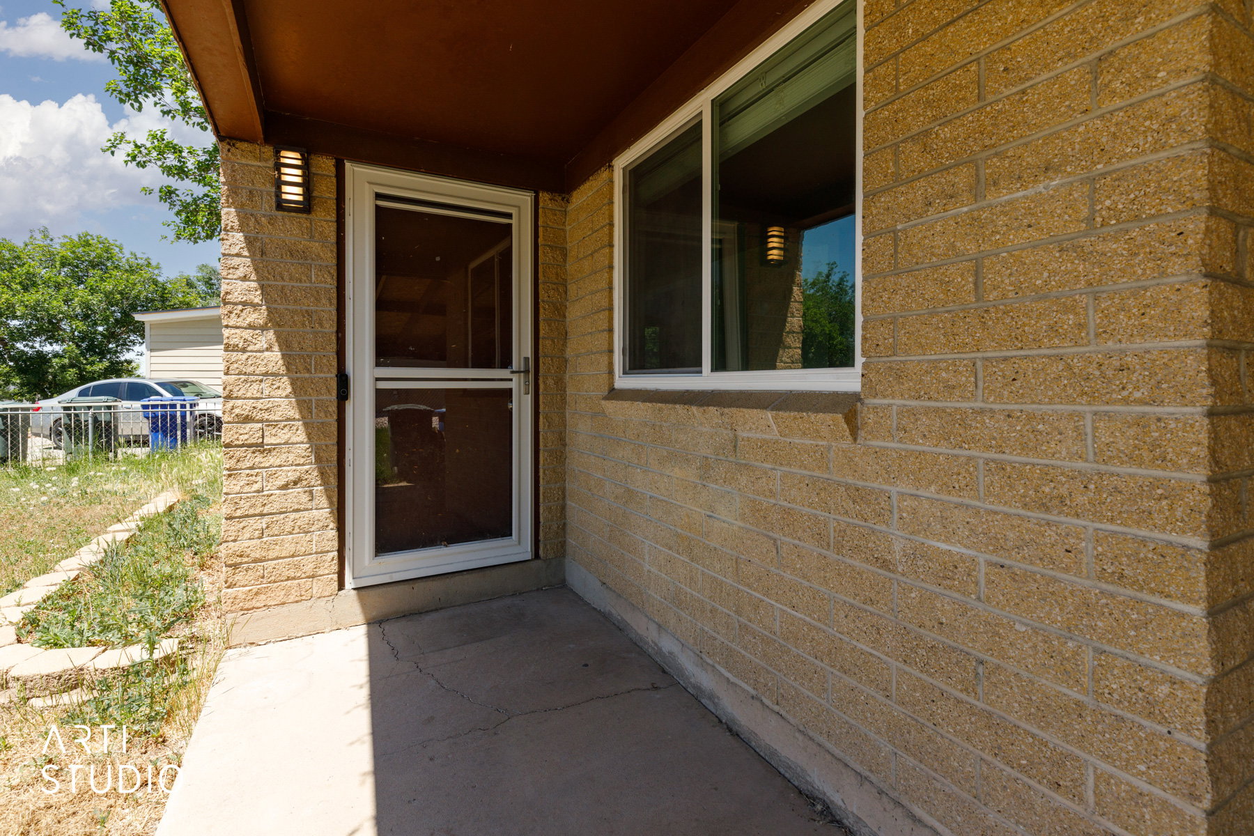Textured brick facade featuring a white-framed storm door and an adjacent window with white trim