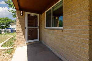 Textured brick facade featuring a white-framed storm door and an adjacent window with white trim