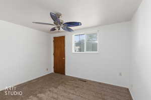 Carpeted room featuring a ceiling fan with integrated lighting, a single window, and a wood-finish door