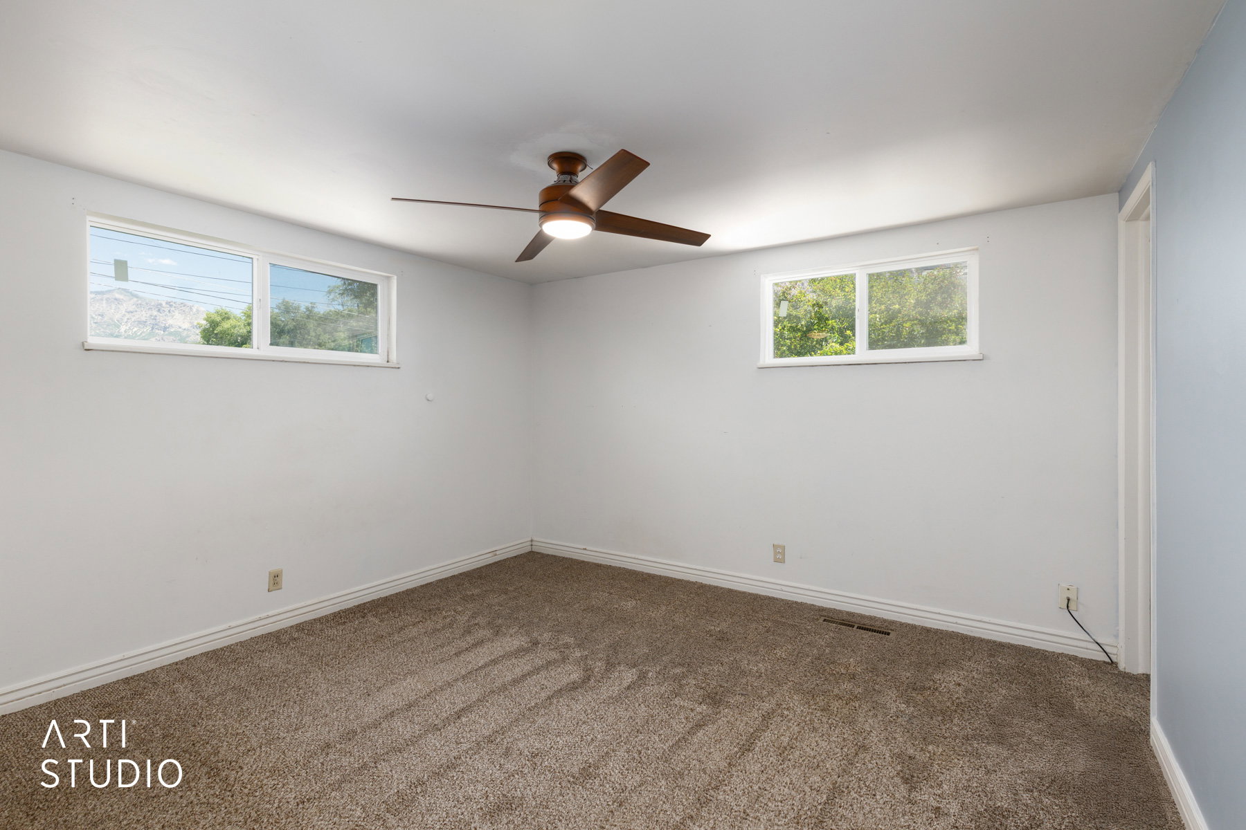 Carpeted room featuring a ceiling fan with integrated lighting, two windows with white trim, and white baseboards