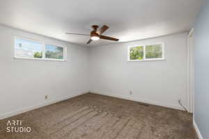 Carpeted room featuring a ceiling fan with integrated lighting, two windows with white trim, and white baseboards