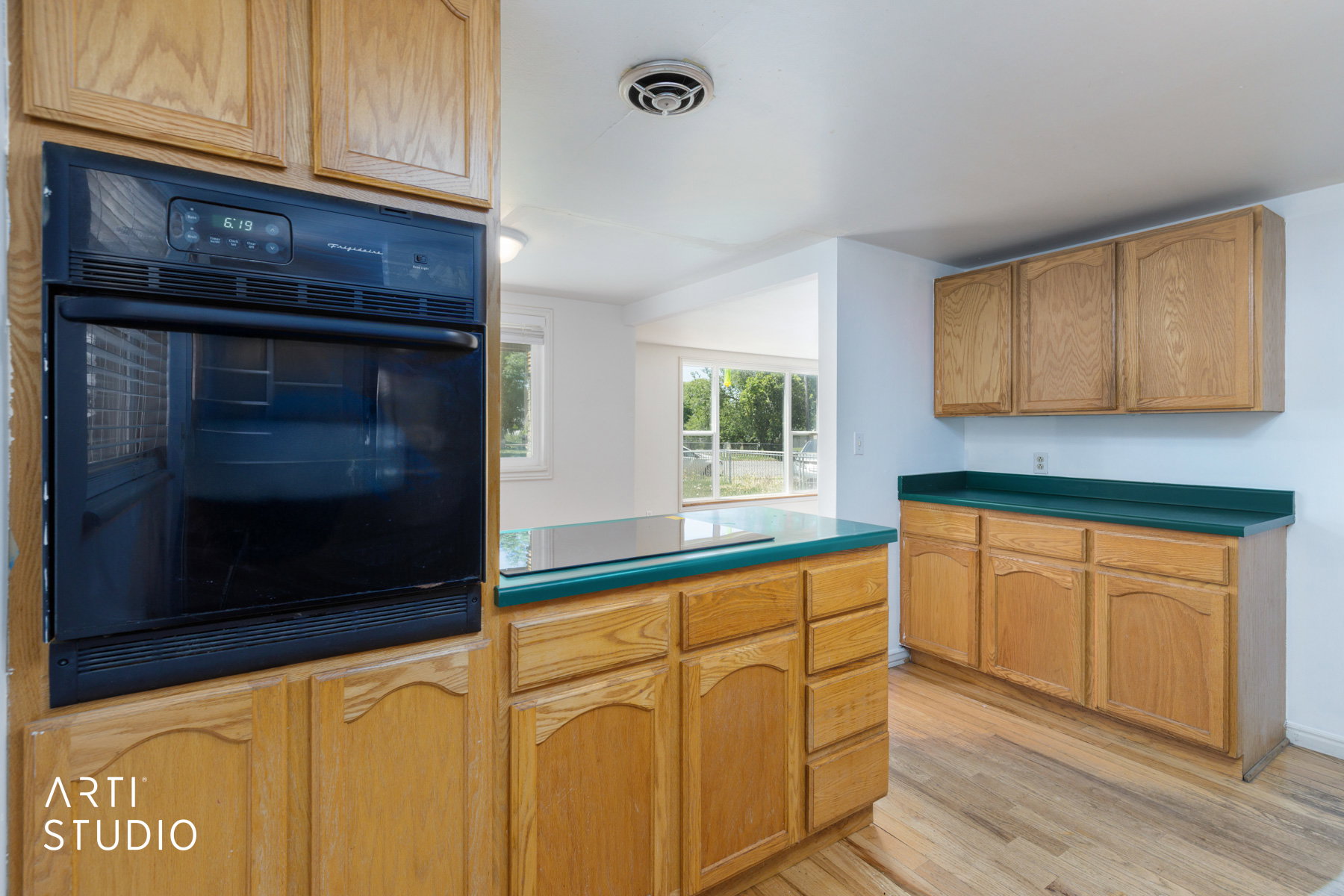 Kitchen featuring a built-in wall oven, wood-finish cabinetry, green countertops, and wood-finish flooring
