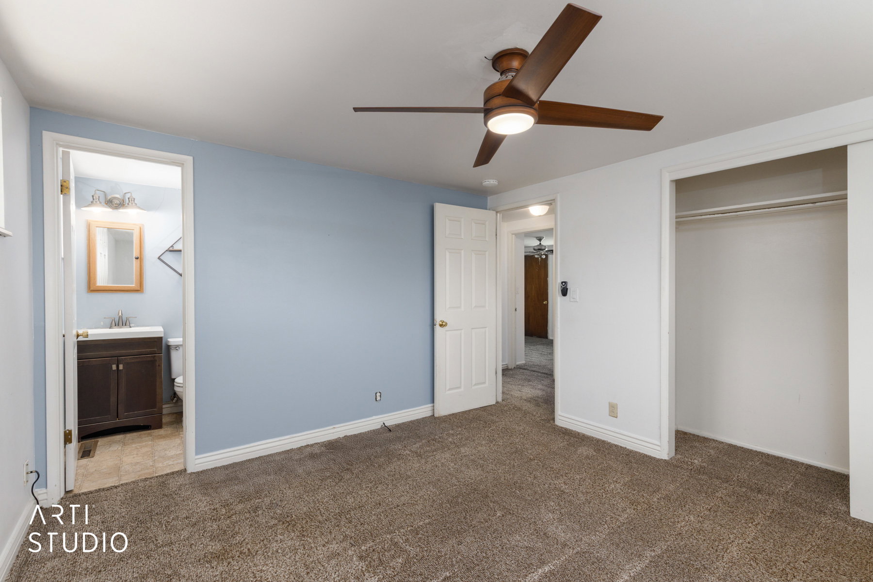 Bedroom with blue accent wall, neutral carpet, and a ceiling fan with integrated lighting