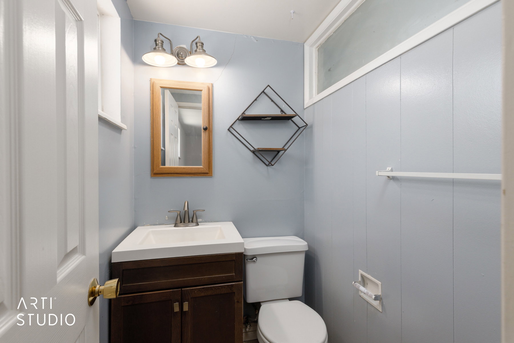 Compact bathroom featuring a dark wood-finish vanity with an integrated white sink, a wall-mounted medicine cabinet, and a horizontal frosted window