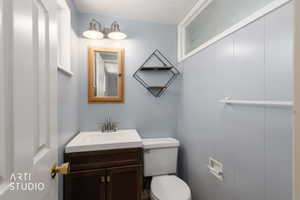Compact bathroom featuring a dark wood-finish vanity with an integrated white sink, a wall-mounted medicine cabinet, and a horizontal frosted window