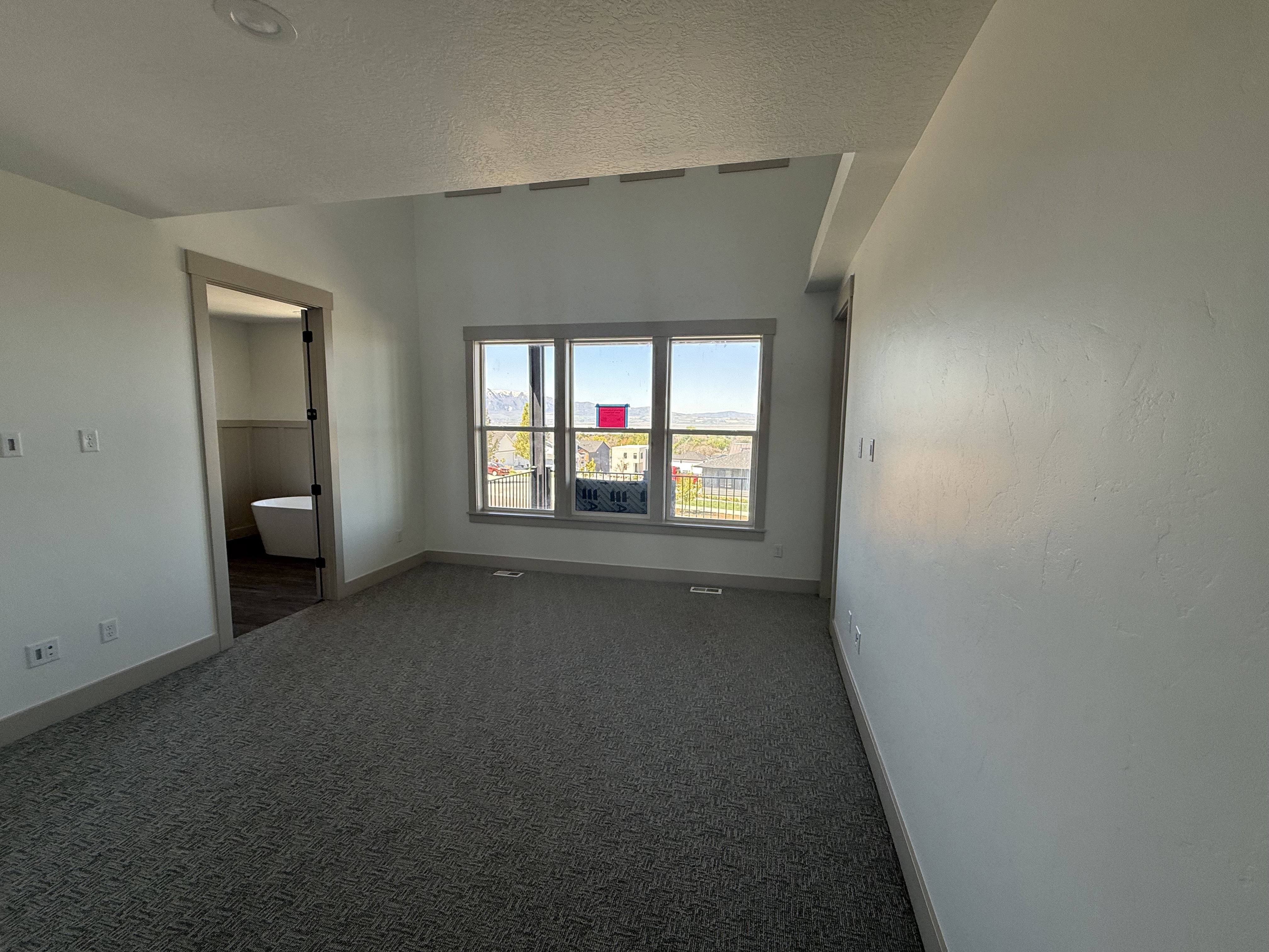 Carpeted interior space with neutral wall tones and a distinct ceiling line