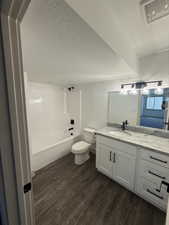 Bathroom featuring wood-finish flooring, a white vanity with shaker-style cabinetry, granite-finish countertop, and black hardware
