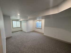 Spacious room featuring new patterned carpet, recessed lighting, two windows with wood-trim surrounds, and light-colored baseboards