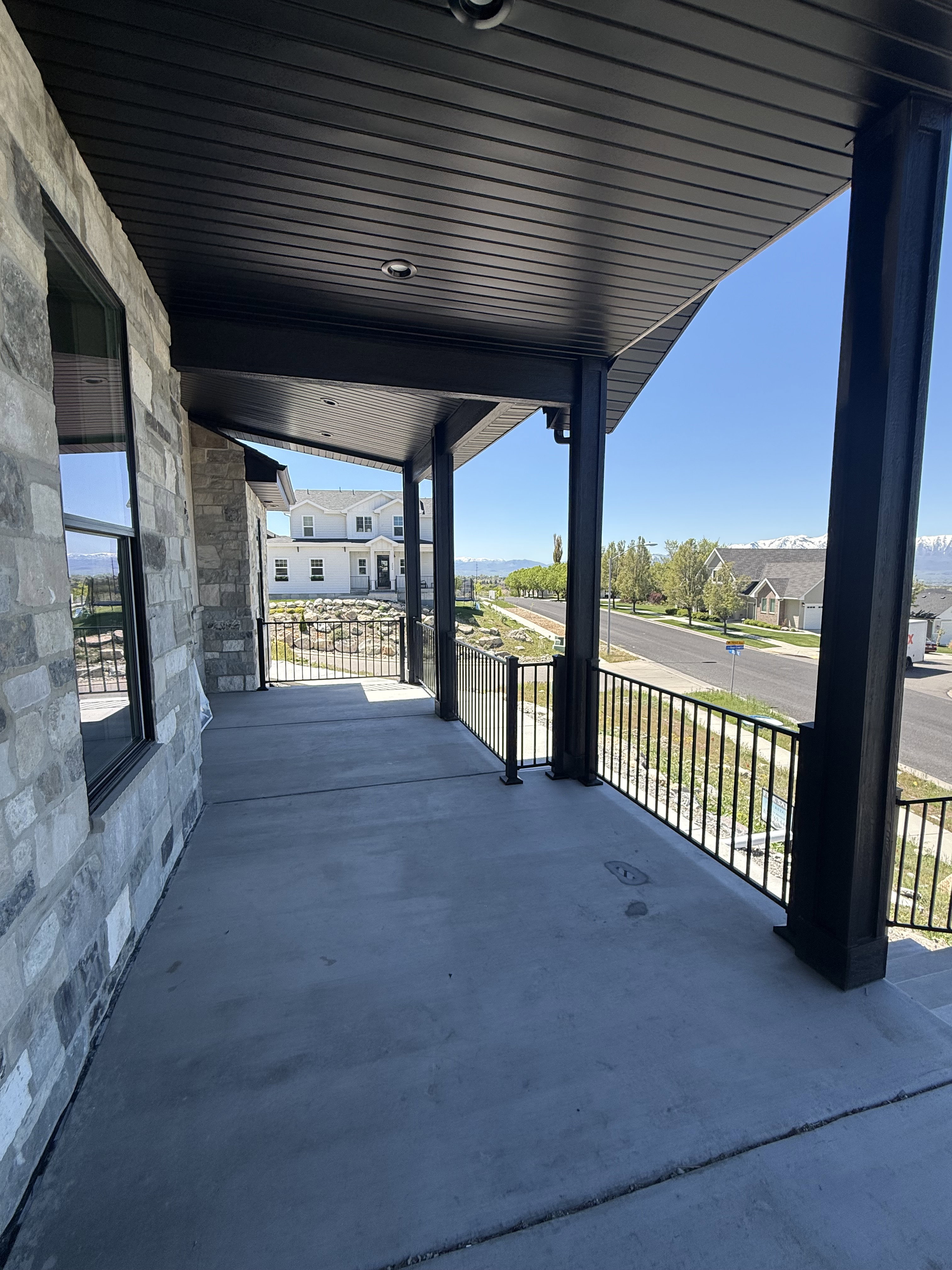 Spacious covered porch with stone-veneer exterior and black metal railing