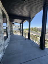 Spacious covered porch with stone-veneer exterior and black metal railing