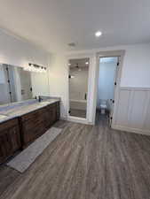 Bathroom featuring a dual vanity with a patterned countertop, rich wood-finish cabinetry, and a framed mirror