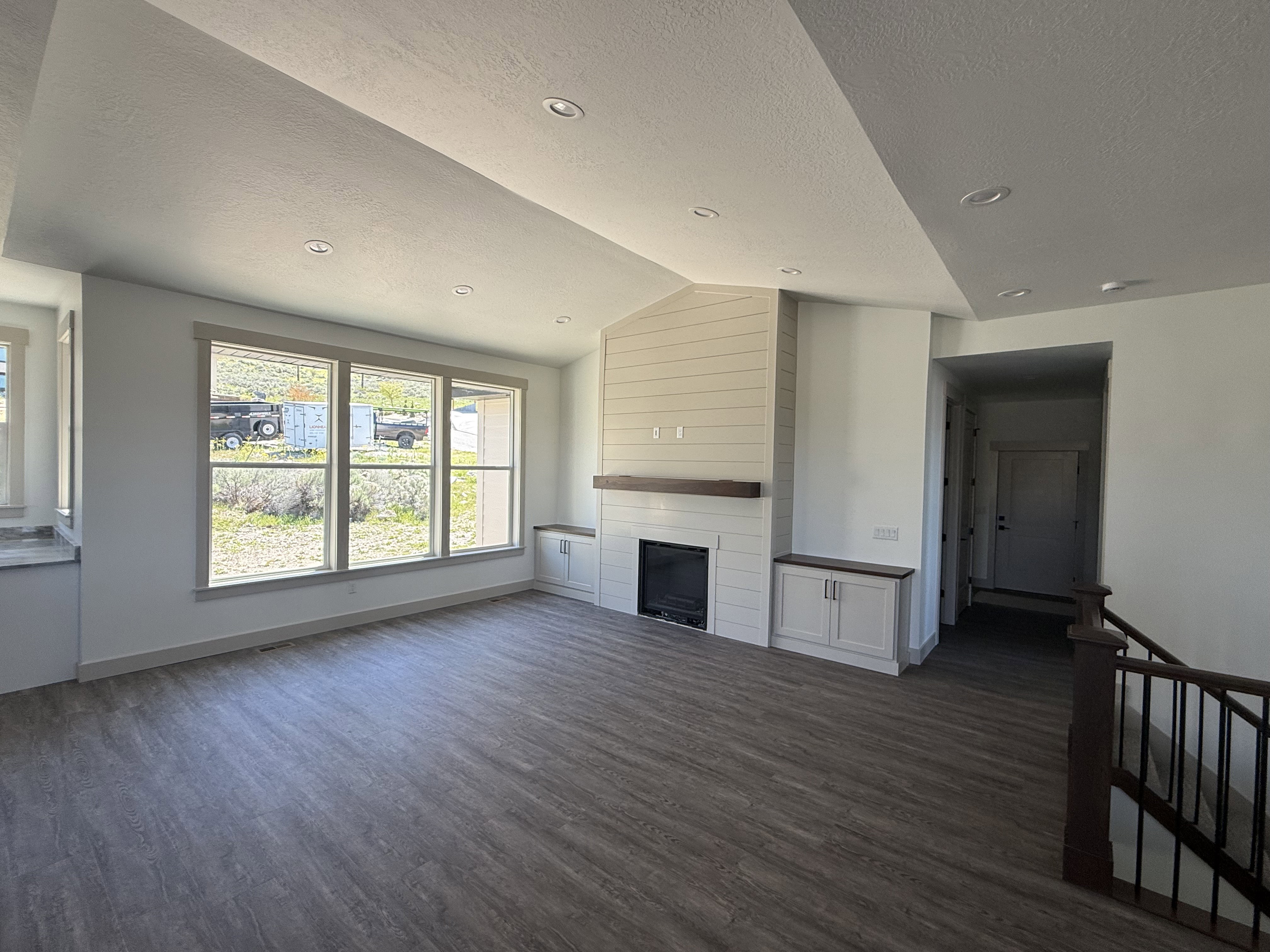 Spacious living area featuring wood-finish flooring and a vaulted ceiling with recessed lighting