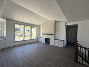 Spacious living area featuring wood-finish flooring and a vaulted ceiling with recessed lighting