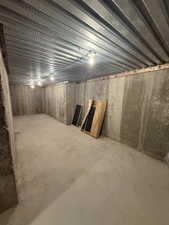 Unfinished basement featuring concrete walls, a concrete floor, and a metal ceiling with exposed lighting fixtures