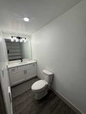 Bathroom featuring a dual-sink vanity with white cabinetry, a light-toned countertop, and dark wood-finish flooring