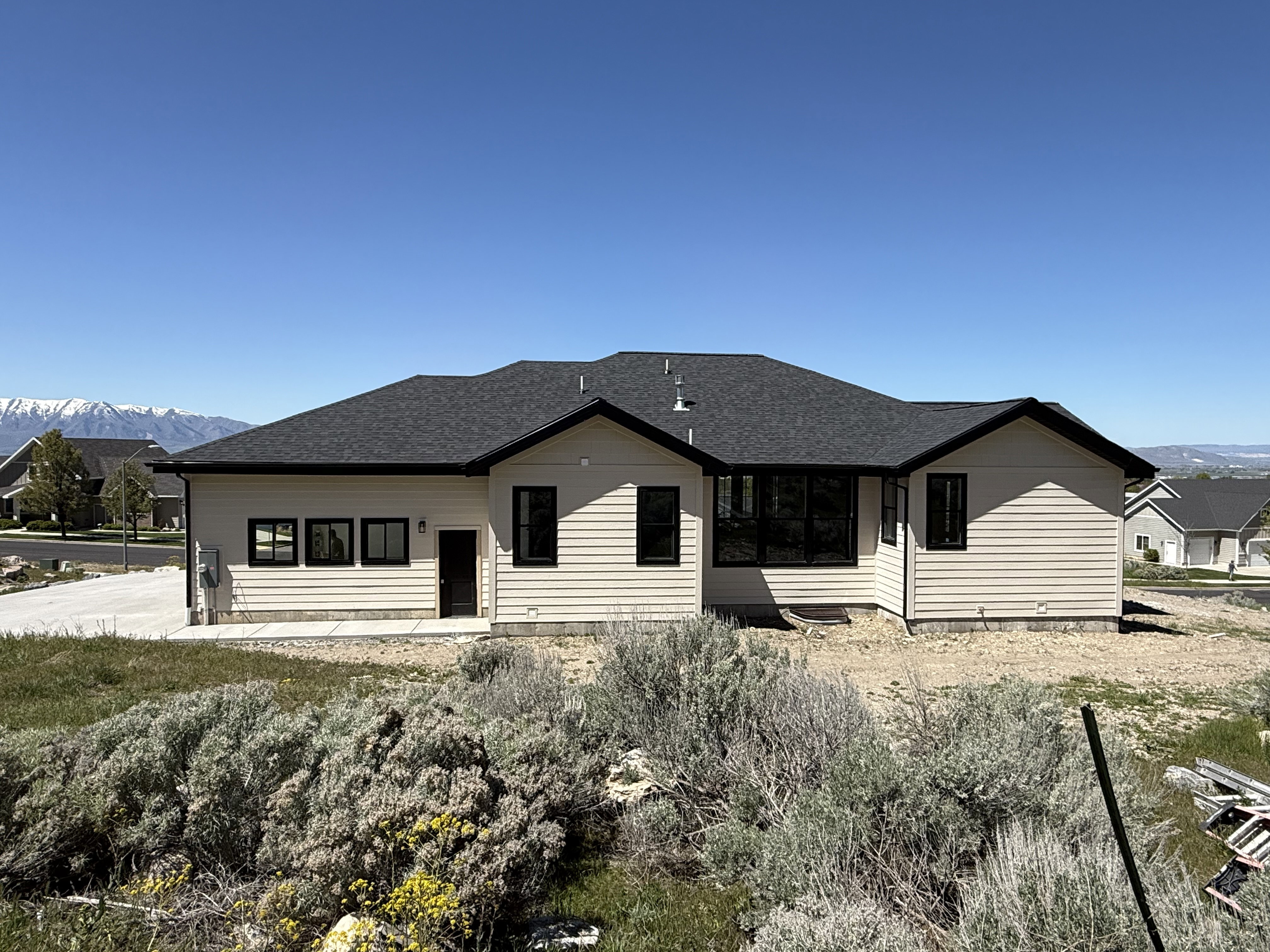 Contemporary ranch-style residence featuring horizontal siding, a dark shingle roof, and contrasting black-framed windows