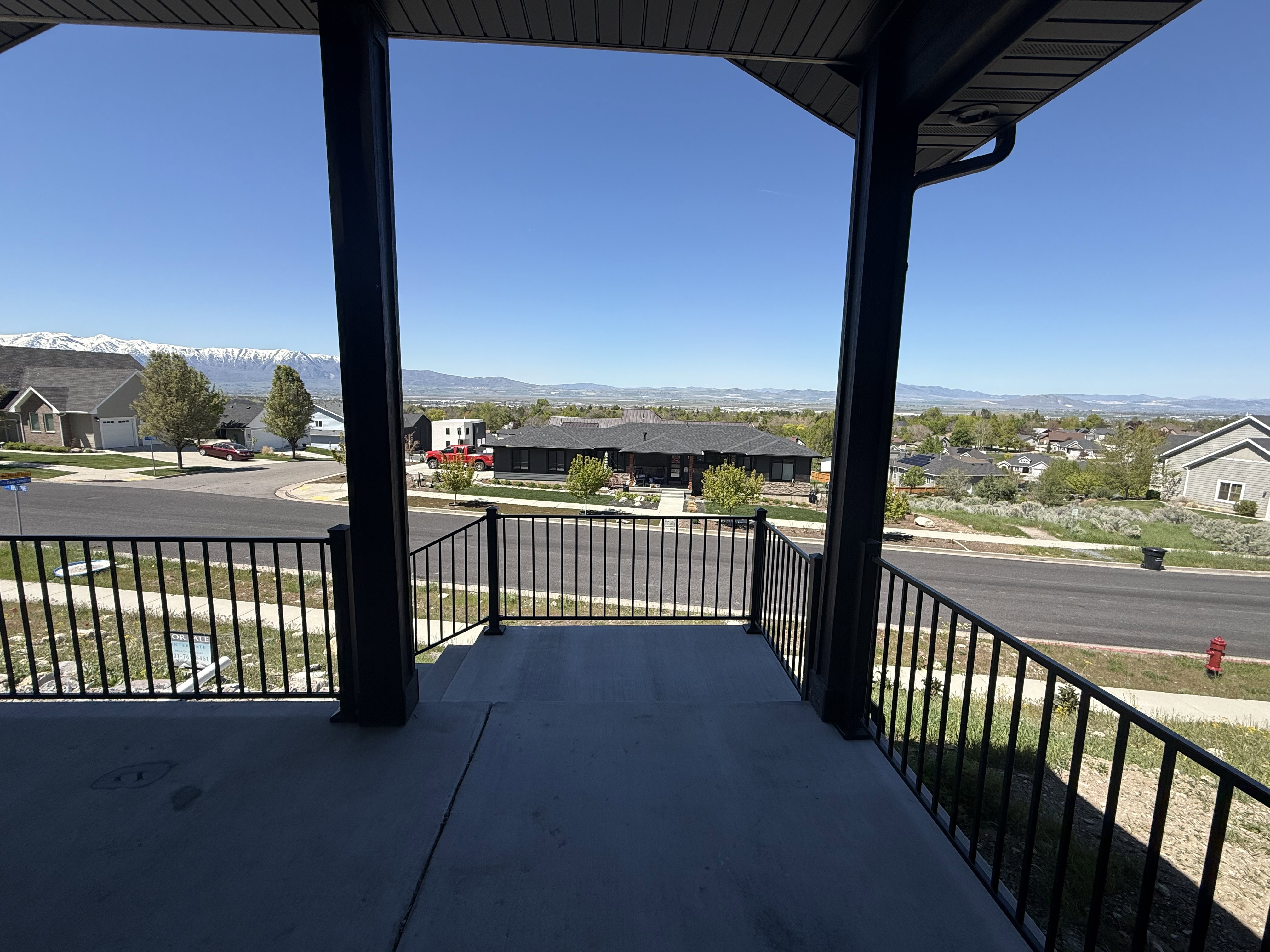 Covered porch with concrete flooring and dark metal railings