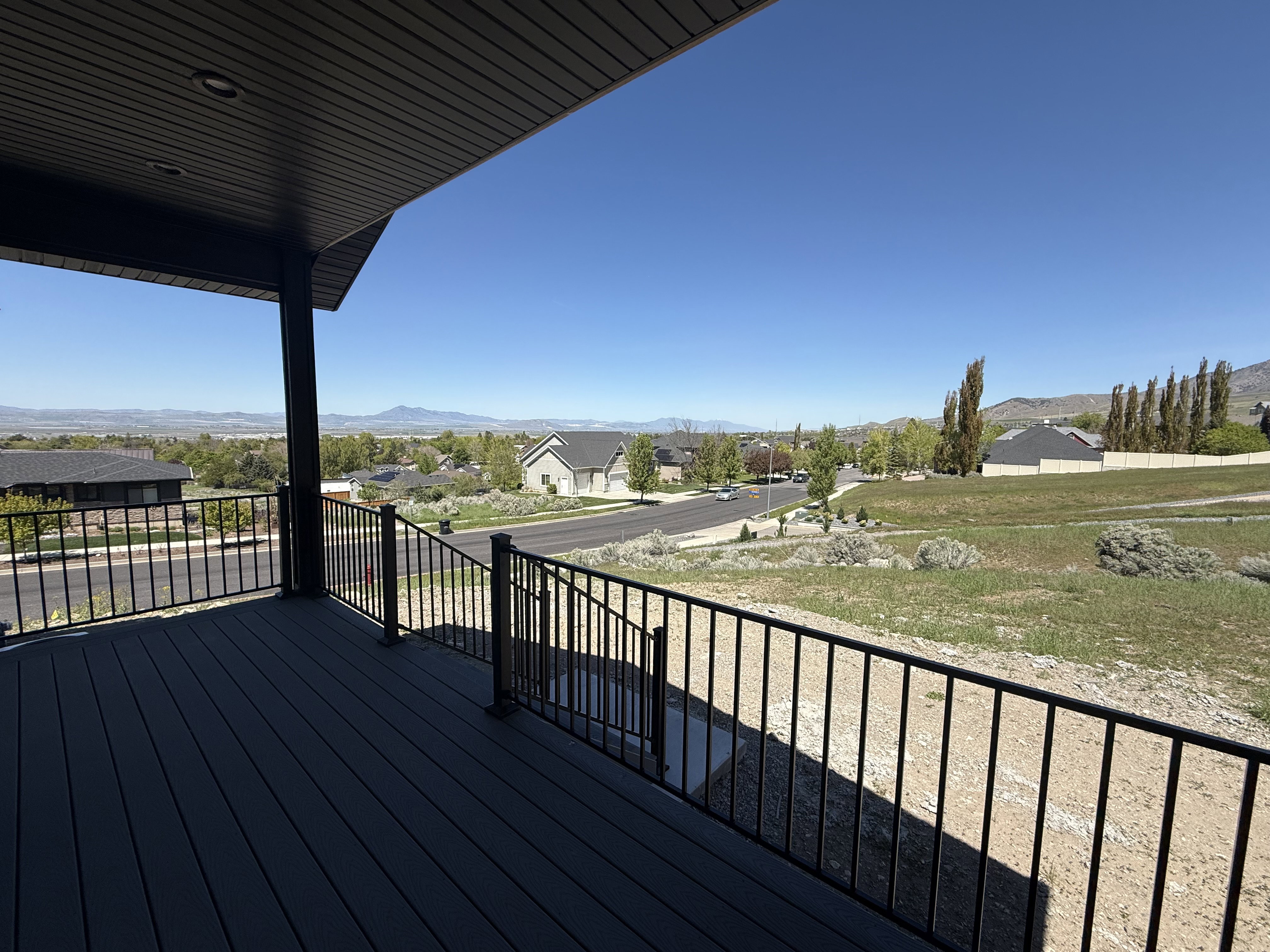 Spacious outdoor deck featuring dark composite decking, black metal railings, and an overhead soffit with recessed lighting