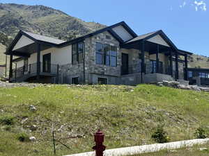 Modern residence featuring a stone and siding exterior, multiple covered patios, black-framed windows, and a black shingle roof