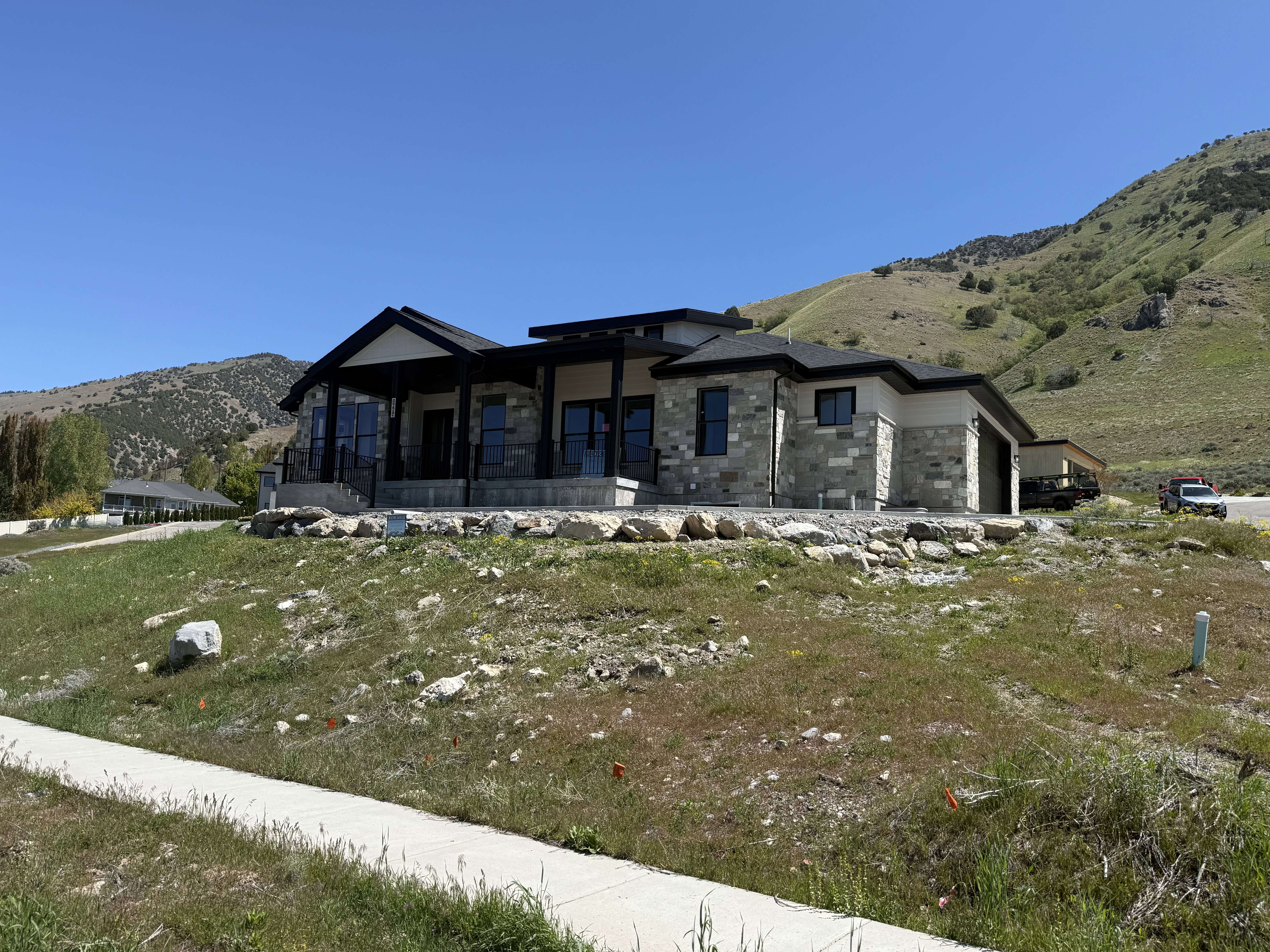 Modern ranch-style residence featuring a stone and siding exterior, dark trim, and a covered entry