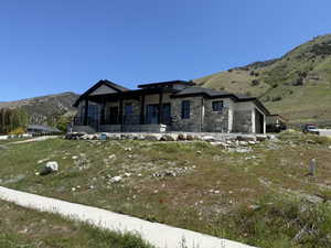 Modern ranch-style residence featuring a stone and siding exterior, dark trim, and a covered entry