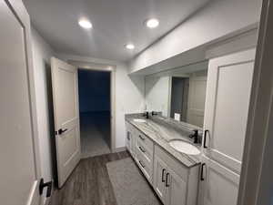 Double vanity featuring white shaker cabinetry, an integrated mirror, and a stone countertop with dual undermount sinks and matte black fixtures