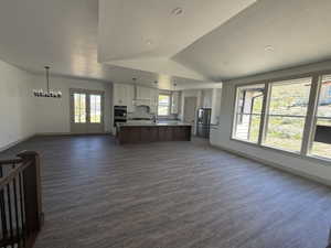 Open-concept living space featuring wood-finish flooring, recessed lighting, and a modern chandelier