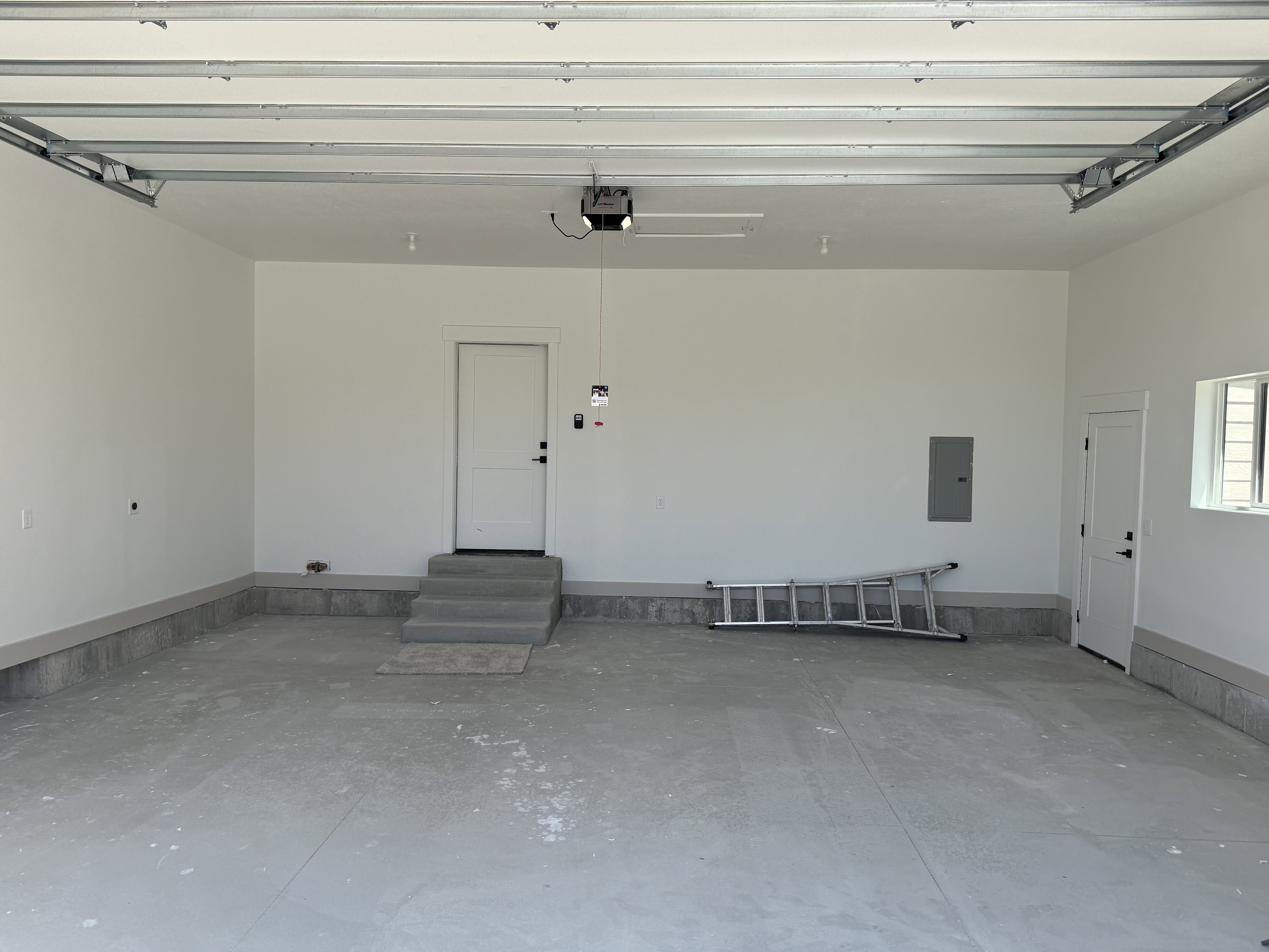 Spacious garage featuring a concrete floor, painted walls, and built-in overhead garage door track system