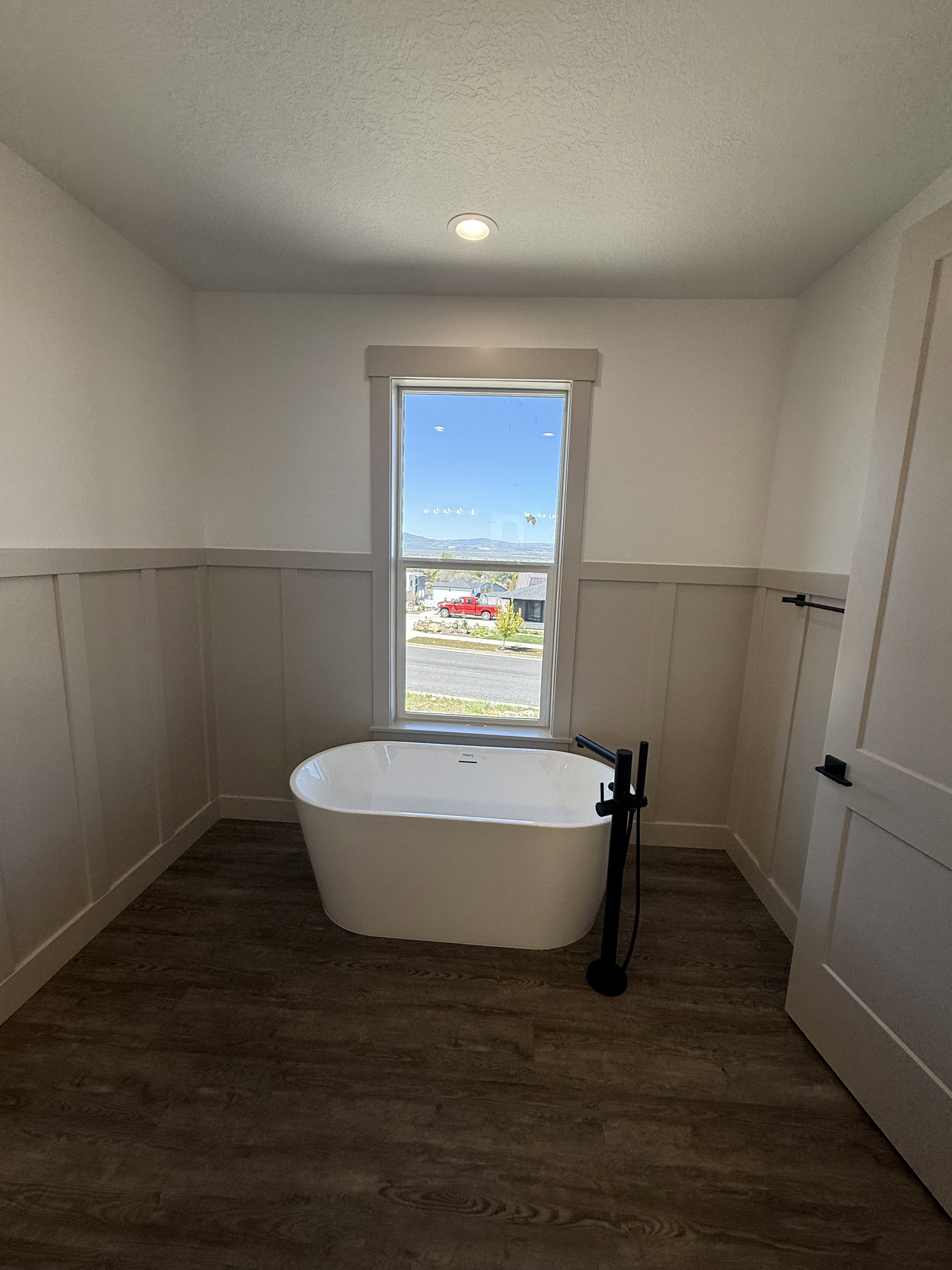 Freestanding soaking tub with a matte black floor-mounted faucet, set against a board and batten wall treatment
