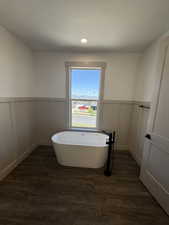 Freestanding soaking tub with a matte black floor-mounted faucet, set against a board and batten wall treatment