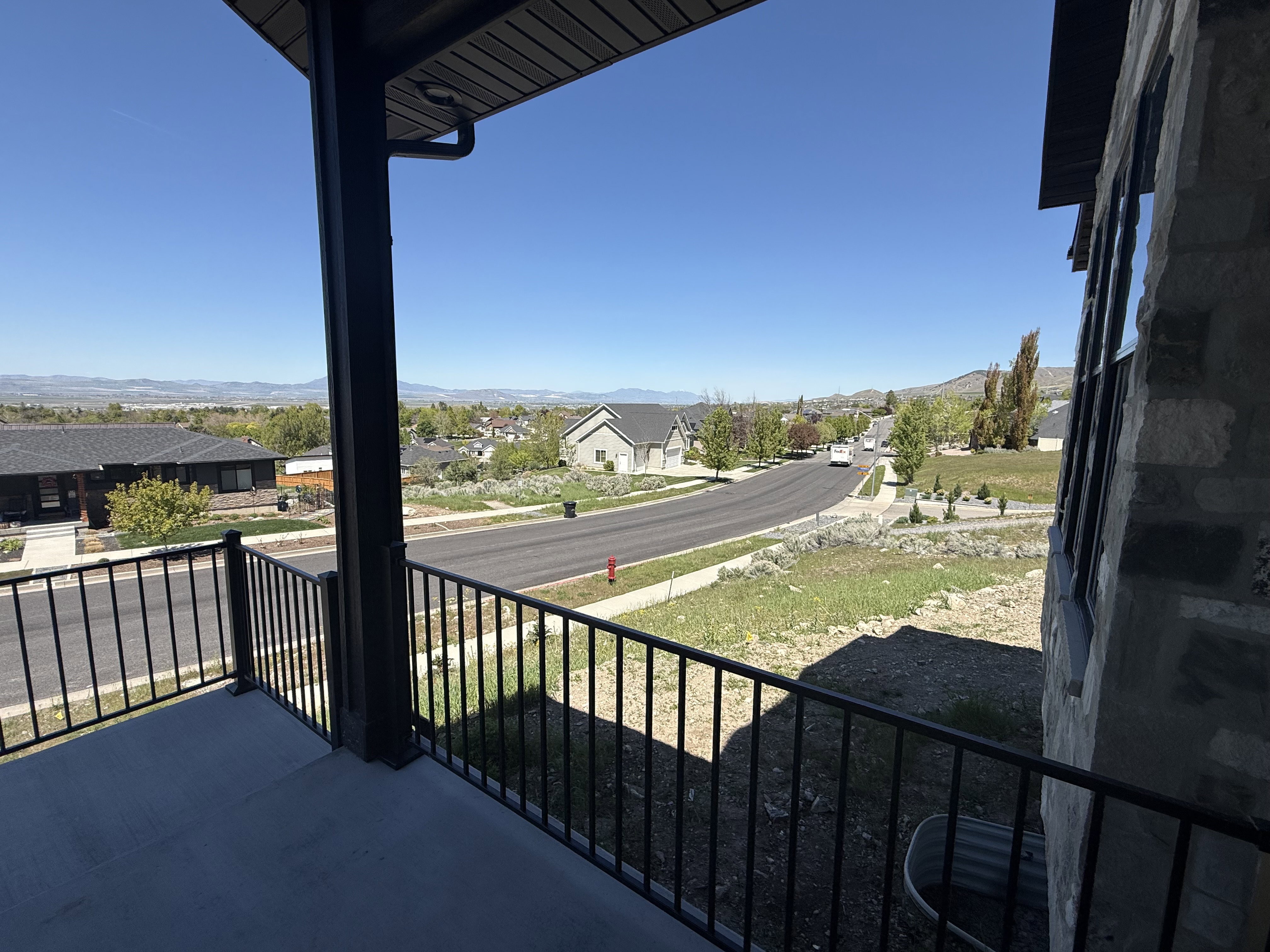 Covered concrete patio featuring black metal railings and a distant mountain backdrop