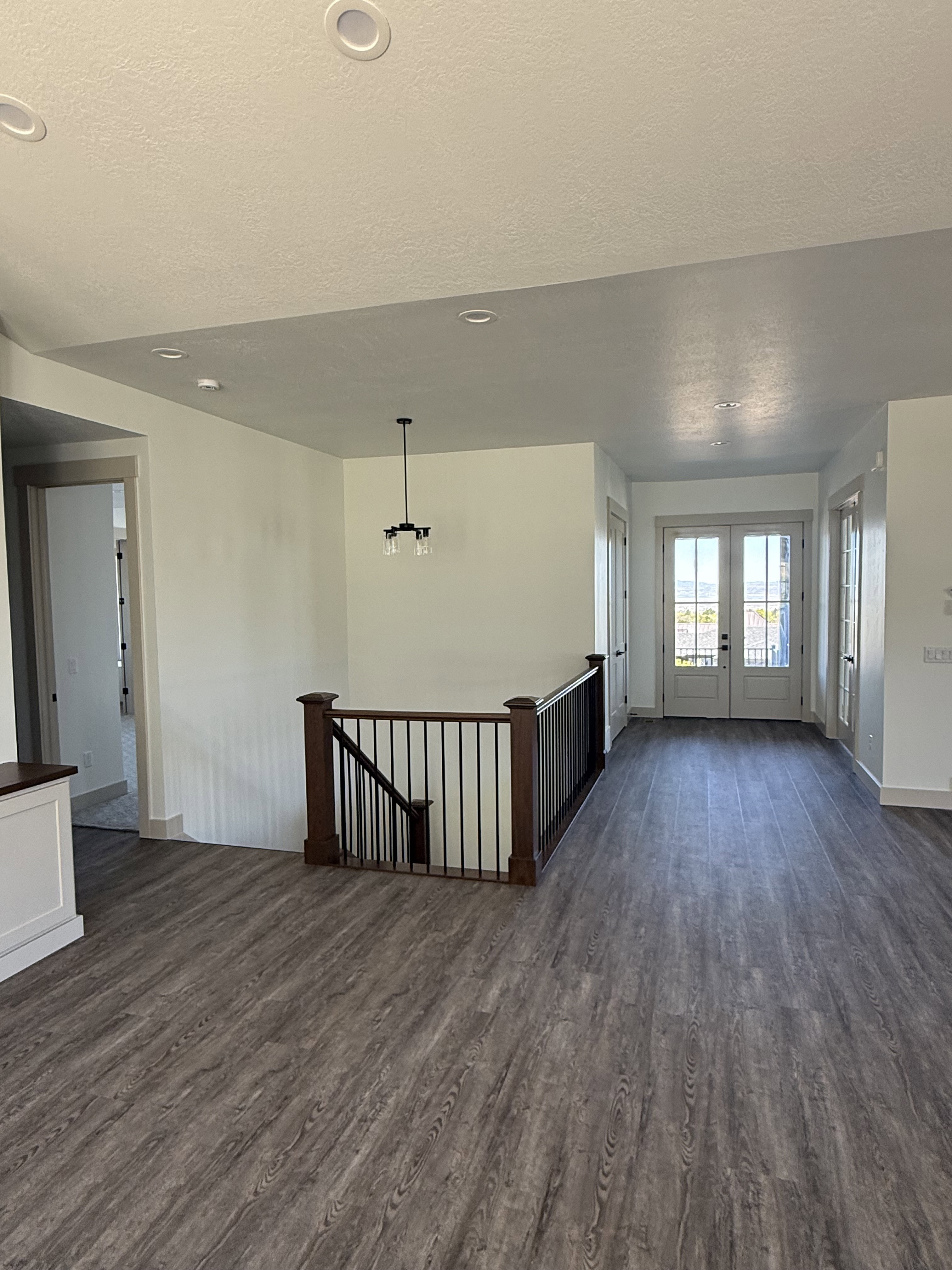 Open-concept living space featuring wood-finish flooring, recessed lighting, and a wrought iron and wood staircase railing